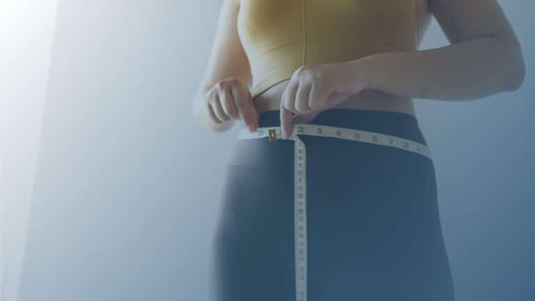 Pessoa medindo a circunferência abdominal com uma fita métrica, simbolizando o acompanhamento da perda de peso.
